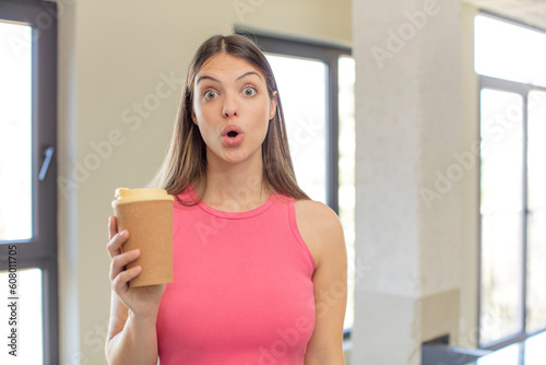 young pretty woman feeling extremely shocked and surprised. take away coffee concept