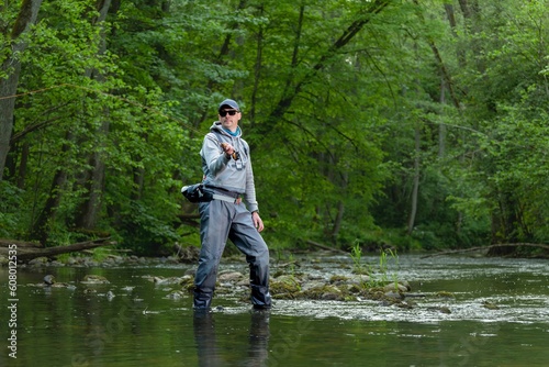 Fisherman catching brown trout on the fly standing in river.