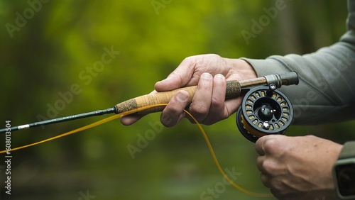 Fisherman catching brown trout on the fly standing in river. Close up.