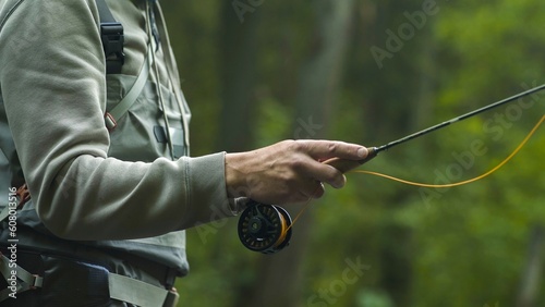 Fisherman catching brown trout on the fly standing in river. Close up.