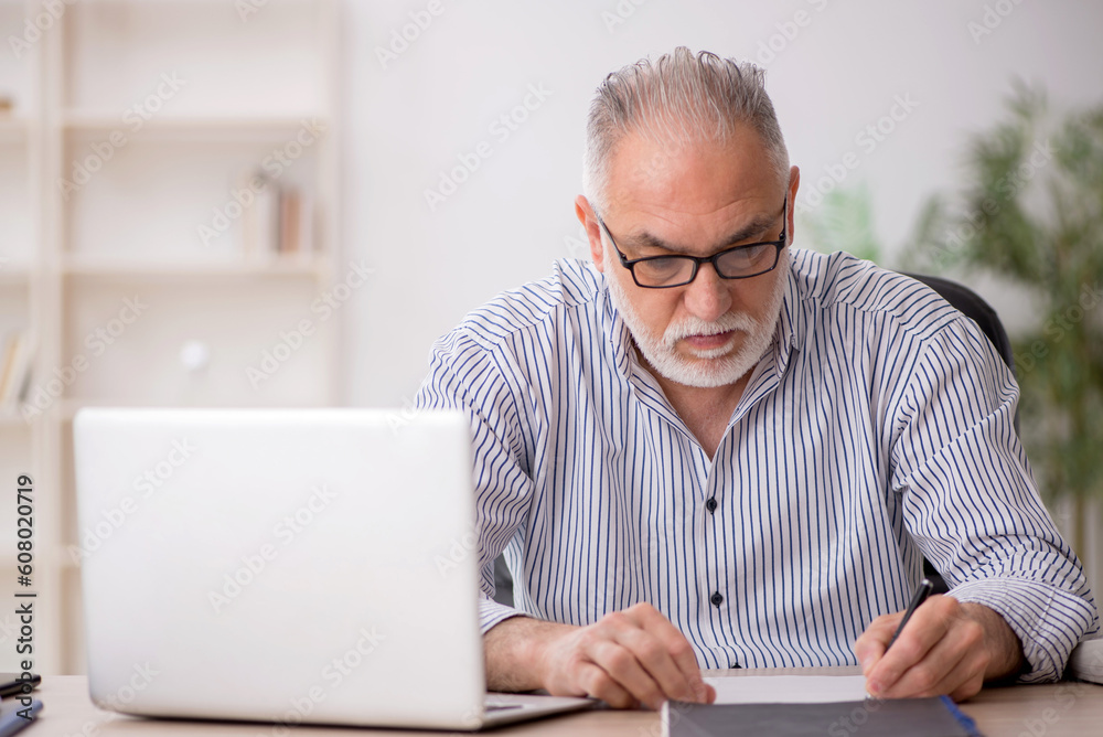 Old male employee working in the office Old male employee working in the office