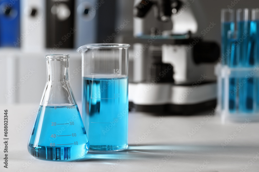 Different laboratory glassware with light blue liquid on table. Space for text Different laboratory glassware with light blue liquid on table. Space for text