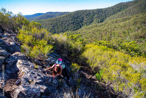 Bautiful adventurer girl climbs the narrow rock walls of the razorback ridge on Pages Pinnacle. Hidden gems in Springbrook National Park, Gold Coast, Queensland, Australia