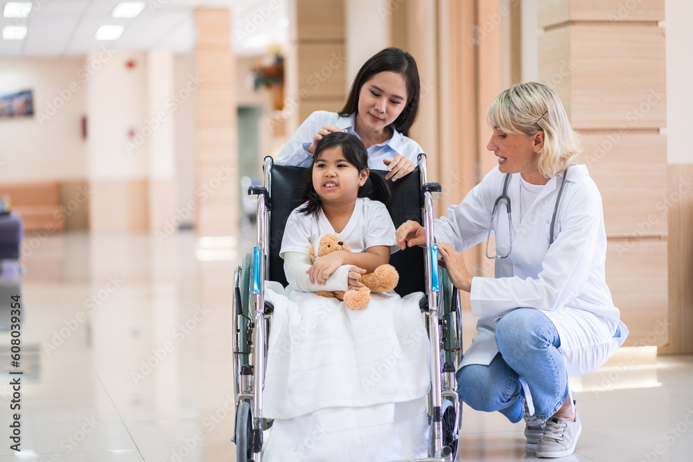 Female pediatrician doctor and child patient on wheelchair with her mother in the health medical center