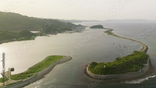 Aerial pullback on sandbar island and seawall protecting small bay photo