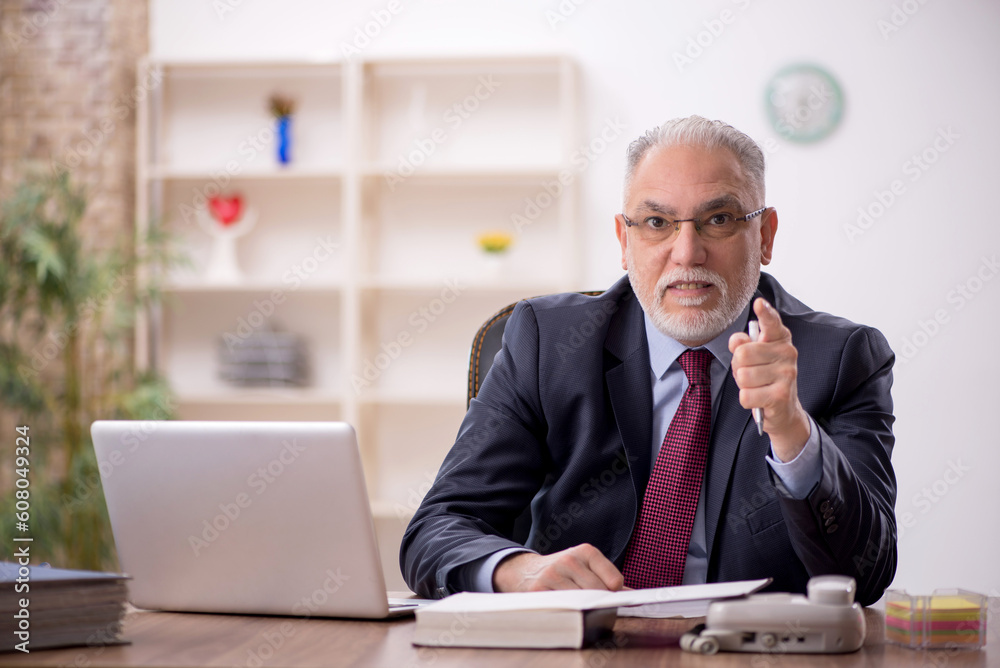 Old male boss working at workplace Old male boss working at workplace