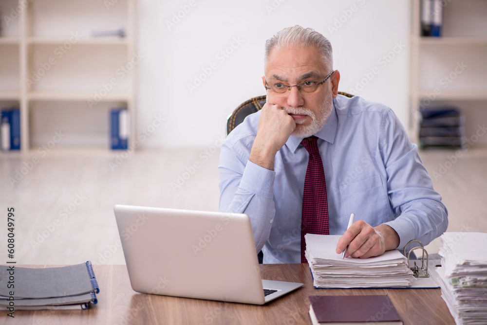 Old male boss working at workplace Old male boss working at workplace
