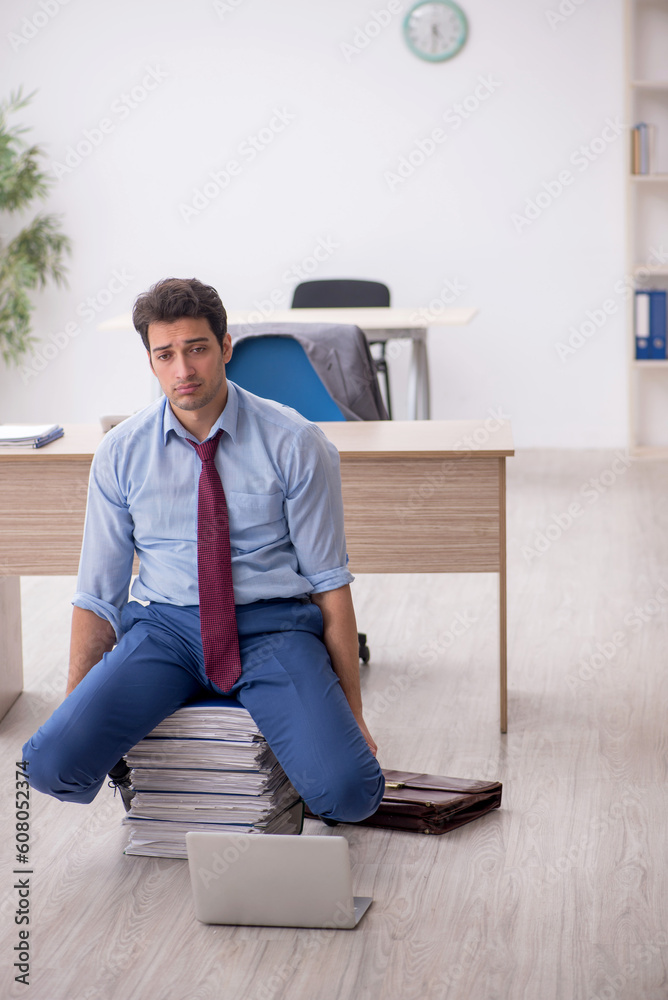 Young male employee unhappy with excessive work in the office Young male employee unhappy with excessive work in the office
