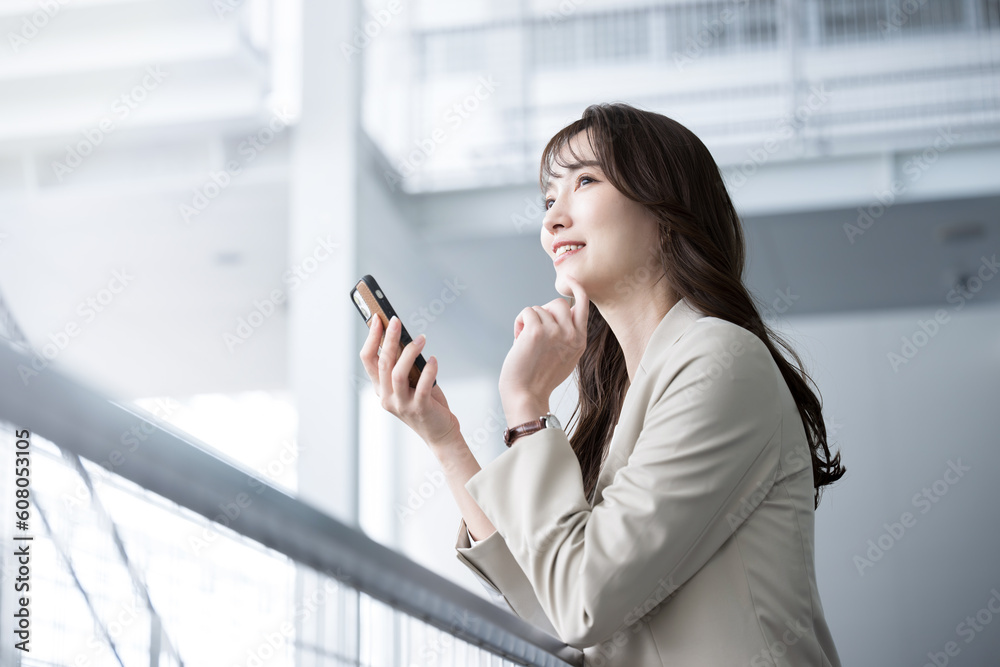 オフィスでスーツ姿でスマホ持つ転職などを迷ったり考える美人な女性 コピースペース オフィスでスーツ姿でスマホ持つ転職などを迷ったり考える美人な女性 コピースペース