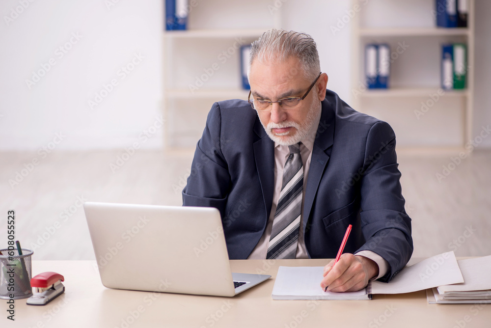 Old male employee working in the office Old male employee working in the office