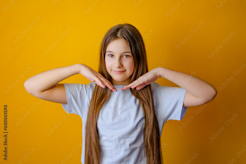 Smiling little girl with long hair holding her hands near her face