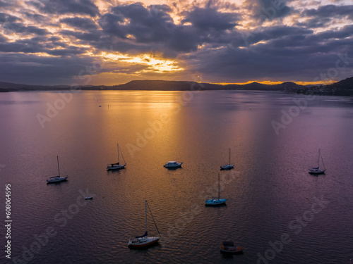 Aerial sunrise over the water with low cloud cover, boats and reflections