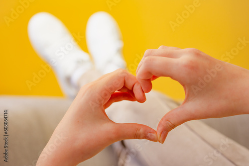 Female child hands in the form of heart on yellow background