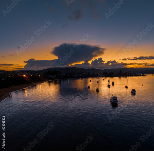 Aerial sunrise waterscape with scattered rain clouds, fog and boats