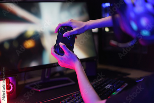 Female cyber hacker gamer use joystick to competition and playing games on computer in neon light