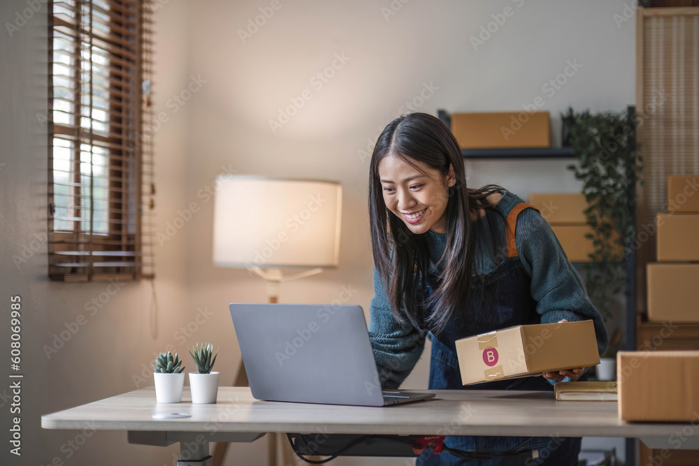 Young beautiful happy asian business woman owner of SME online using laptop receive order from customer with parcel box packaging at her startup home office, online business seller Young beautiful happy asian business woman owner of SME online using laptop receive order from customer with parcel box packaging at her startup home office, online business seller