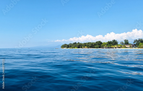 A tropical island in the middle of the blue ocean under the blue sky