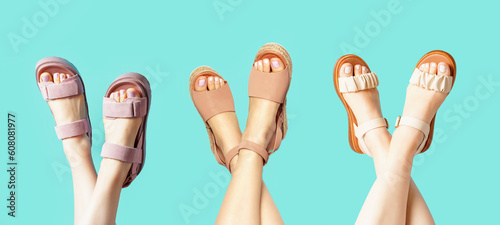 Female legs with pedicure brown sandals on blue background, copy space.