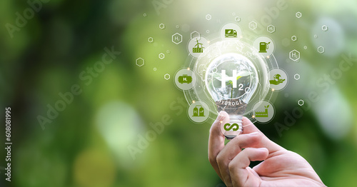 Monlikul's clean hydrogen energy in the concept of environmentally friendly industry. Hand holding a light bulb with clean hydrogen and alternative energy icons. Green energy in the future