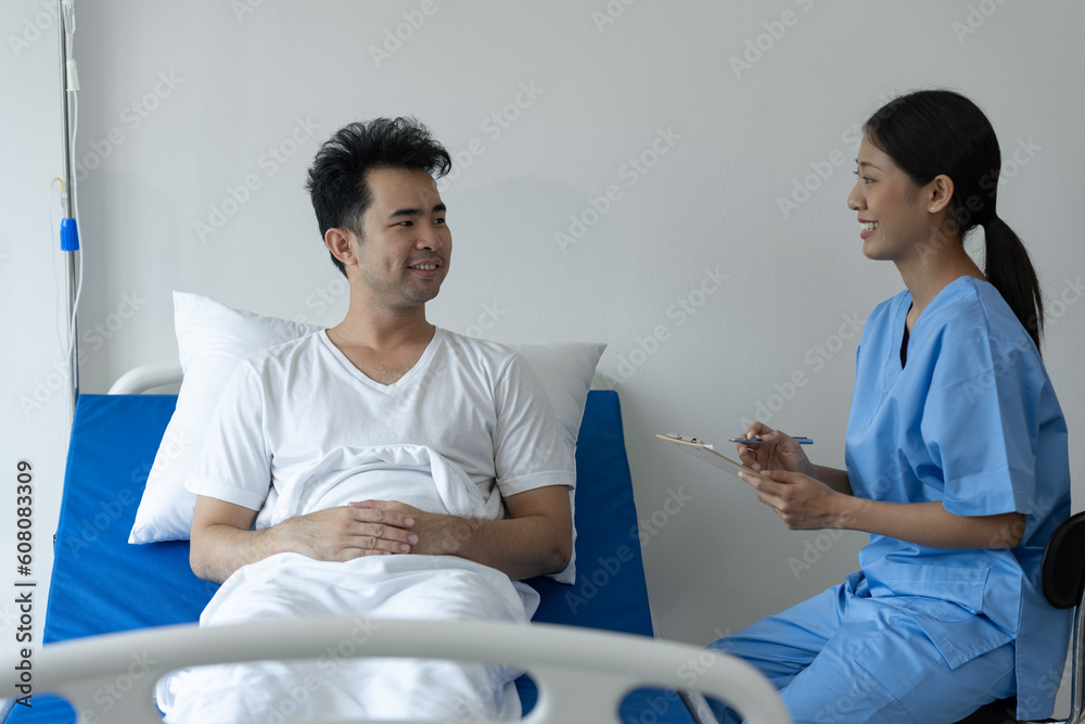 Physiotherapist giving advice and encouragement to male patient doing physiotherapy lying on patient bed to improve mentally and physically Psychological concept, health insurance. Physiotherapist giving advice and encouragement to male patient doing physiotherapy lying on patient bed to improve mentally and physically Psychological concept, health insurance.