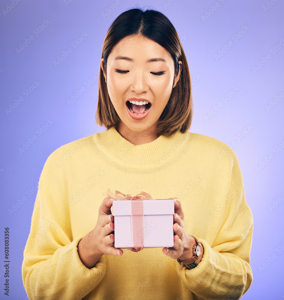 Happy, surprise and woman with a gift in a studio for birthday celebration with a wow face. Happiness, excited and Asian female model with a present, box or package isolated by a purple background. Happy, surprise and woman with a gift in a studio for birthday celebration with a wow face. Happiness, excited and Asian female model with a present, box or package isolated by a purple background.