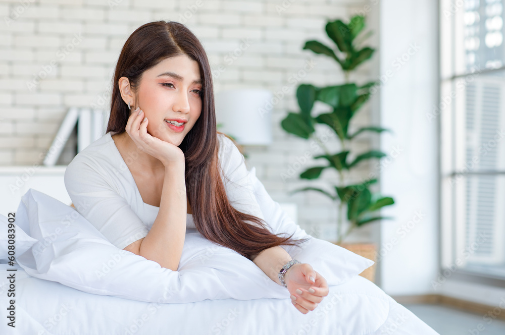 Portrait closeup shot of Millennial Asian beautiful cheerful happy female model in casual outfits with wrist watch laying lying down on white pillow posing smiling look at camera on bed in bedroom Portrait closeup shot of Millennial Asian beautiful cheerful happy female model in casual outfits with wrist watch laying lying down on white pillow posing smiling look at camera on bed in bedroom