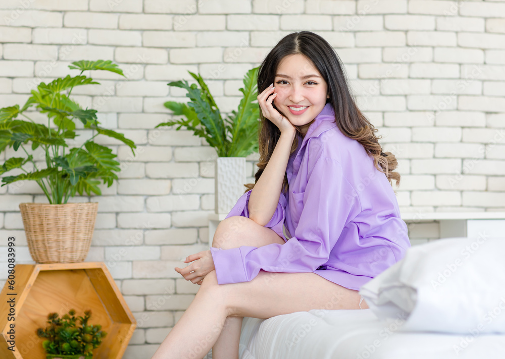 Portrait closeup shot Millennial Asian beautiful cheerful happy female model in casual long sleeve shirt outfit sitting smiling posing on white clean sheet bed with pillow look at camera in bedroom Portrait closeup shot Millennial Asian beautiful cheerful happy female model in casual long sleeve shirt outfit sitting smiling posing on white clean sheet bed with pillow look at camera in bedroom