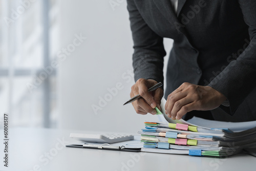 Businesswoman hands working in piles of paper documents looking for market and financial data report on desk, business report paper, stack of papers. Unfinished folder sheet business idea.