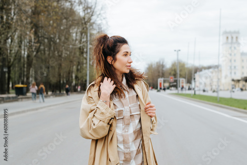 Young mixed race woman in raincoat posing outdoors looking away