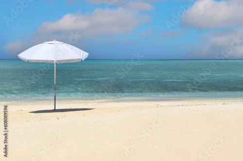 Summer tropical with white umbrella on the beach with blue sky background