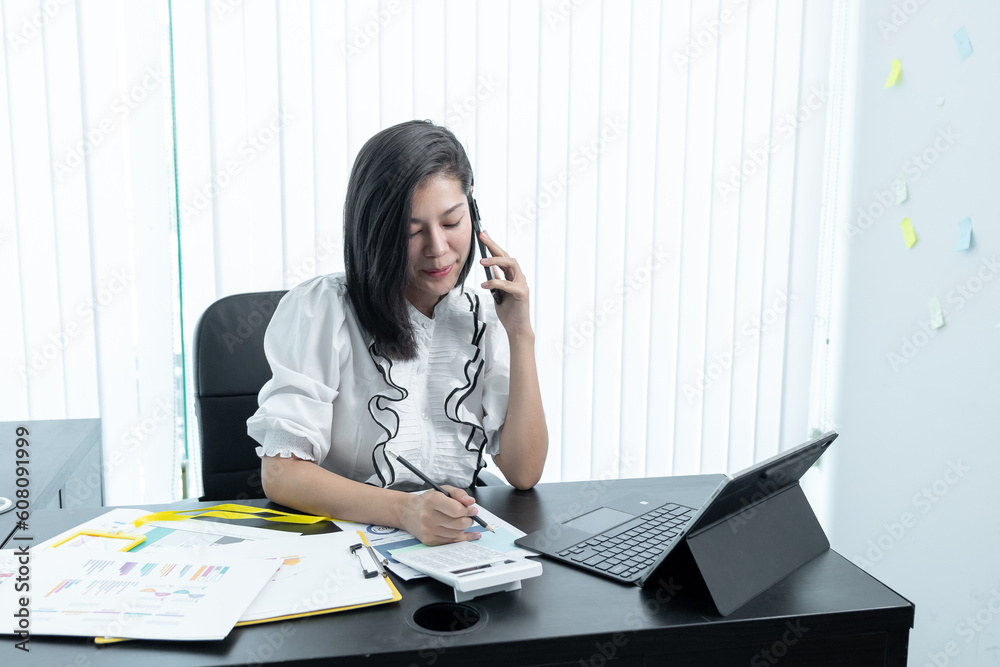 Happy business woman talking on mobile phone while analyzing weekly schedule in her notebook Happy business woman talking on mobile phone while analyzing weekly schedule in her notebook