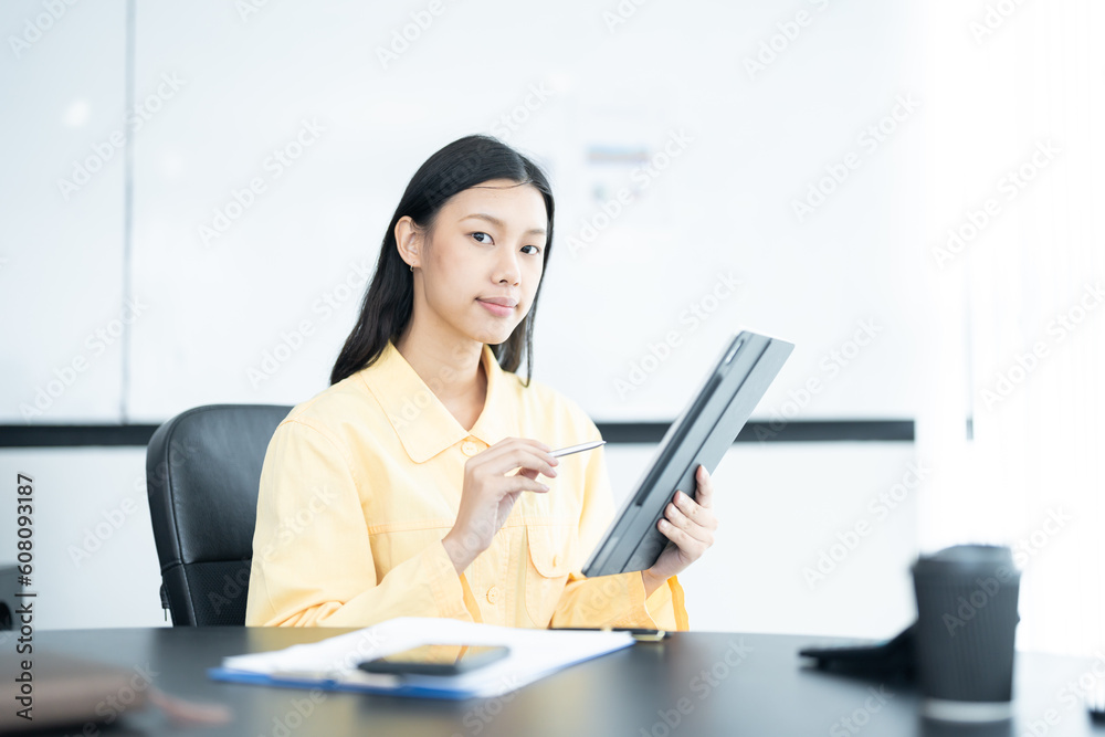 Confident businesswoman holding tablet and smiling at the camera, in meeting room on white background.