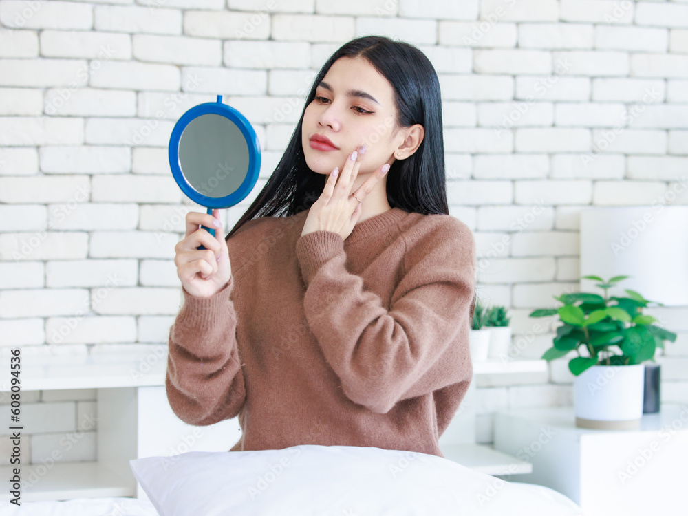 Millennial Asian beautiful cheerful happy female model in casual long sleeve sweater shirt outfit sitting smiling using brush on brushing cosmetic on cheek looking reflection from handheld mirror Millennial Asian beautiful cheerful happy female model in casual long sleeve sweater shirt outfit sitting smiling using brush on brushing cosmetic on cheek looking reflection from handheld mirror