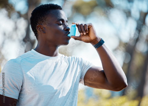 Man, outdoor and asthma inhaler to breathe with allergies, asma or lungs problem while running. Black male runner with emergency medicine pump for health and breathing in a spring forest in nature photo