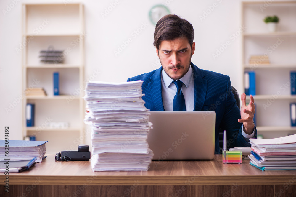 Young businessman employee unhappy with excessive work in the office Young businessman employee unhappy with excessive work in the office