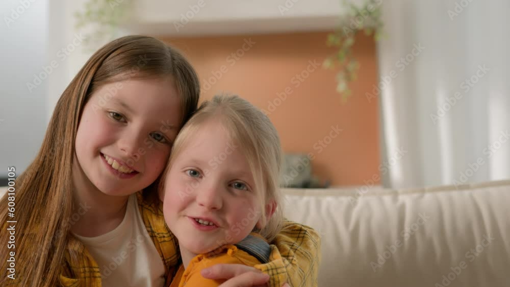 Portrait happy cute little caucasian girls children sisters kids friends smiling look at each other hugging embracing cuddle looking camera family love care affection relationship embrace hug indoors
