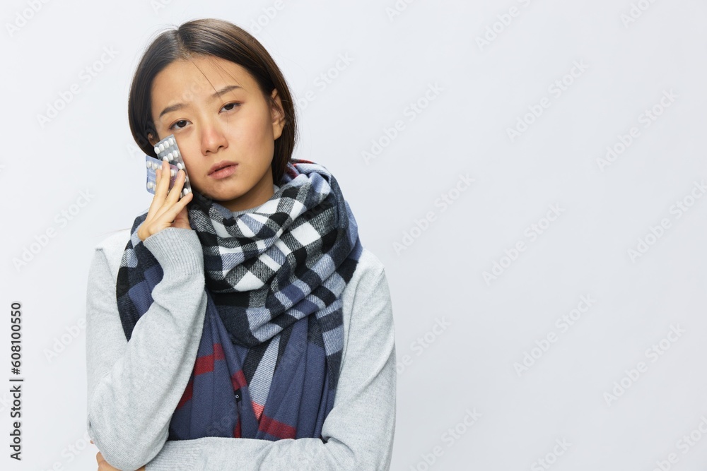Asian woman headache cold flu holding medicine and pills in checkered plaid with fever sick of virus on white background, copy space Asian woman headache cold flu holding medicine and pills in checkered plaid with fever sick of virus on white background, copy space