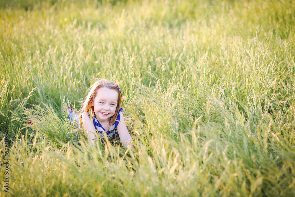 Lovely caucasian girl with long hair lying in long grass at the park with big smile Lovely caucasian girl with long hair lying in long grass at the park with big smile