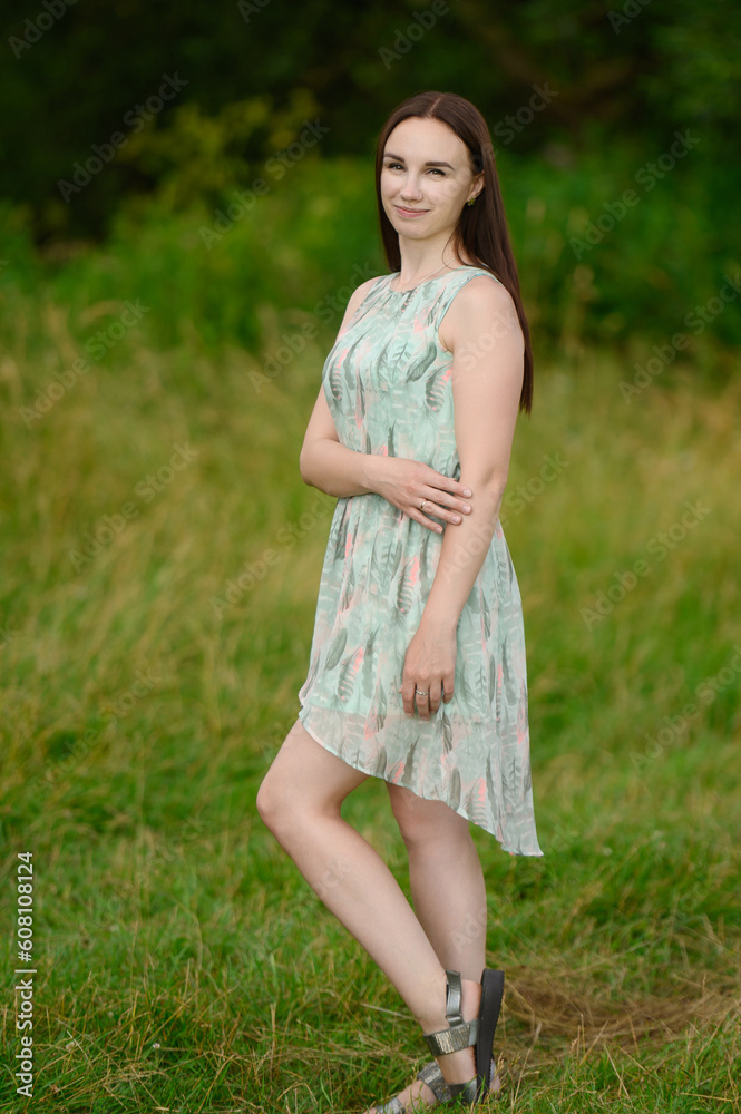 Summer portrait of happy woman in dress standing in city park.The concept of lifestyle,travel,vacation,unity with nature Summer portrait of happy woman in dress standing in city park.The concept of lifestyle,travel,vacation,unity with nature