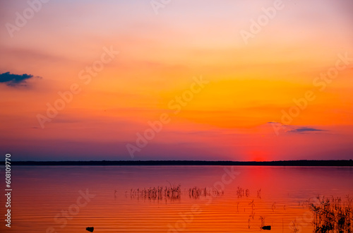Beautiful orange sunset above the lake. Purple sky with clouds. Last ray. Seascape. Calm water. Natural background. Nature landscape. Summertime travelling. Warm evening concept. No people. Morning 
