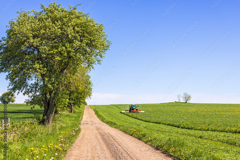 Rural landscape view with a Tractor that harvesting grass on the field Rural landscape view with a Tractor that harvesting grass on the field
