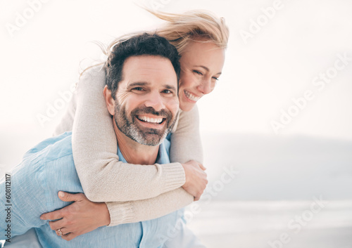 Beach, piggyback and portrait of couple with smile on holiday, vacation and weekend for anniversary. Love, marriage and happy mature man carry woman for bonding, quality time and happiness by ocean #608112117