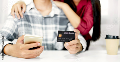 E-commerce Concept. Happy couple holding credit and using smartphone enter their card number in the mobile phone app to purchase and payment in internet store