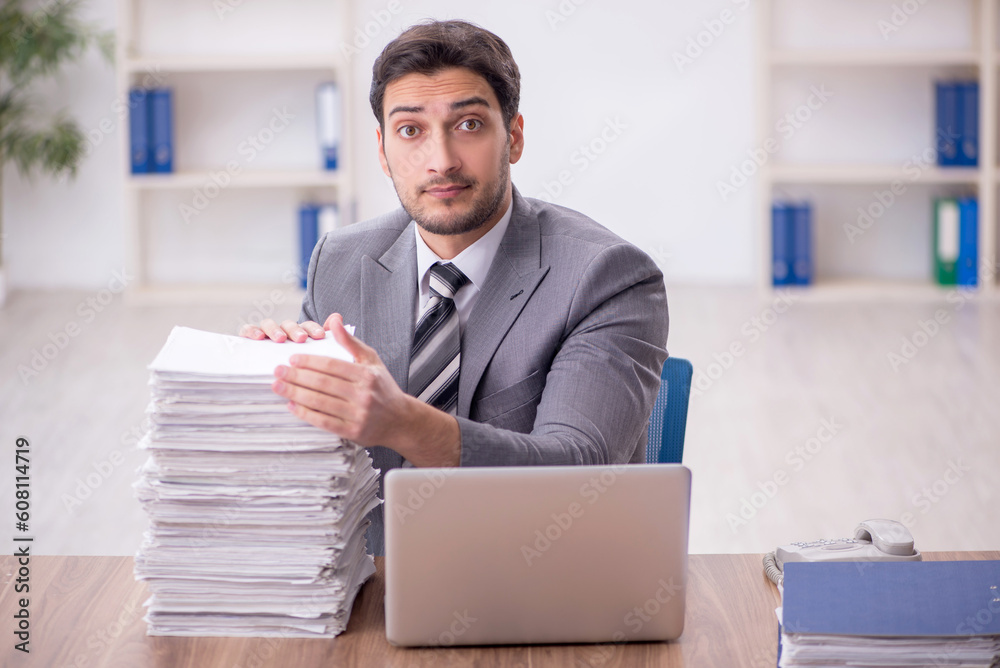 Young male employee and too much work in the office Young male employee and too much work in the office