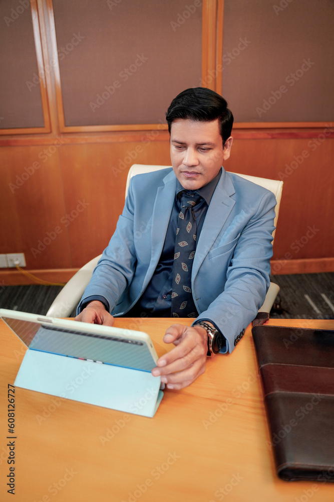 Young indian businessman using tablet or i pad at office Young indian businessman using tablet or i pad at office