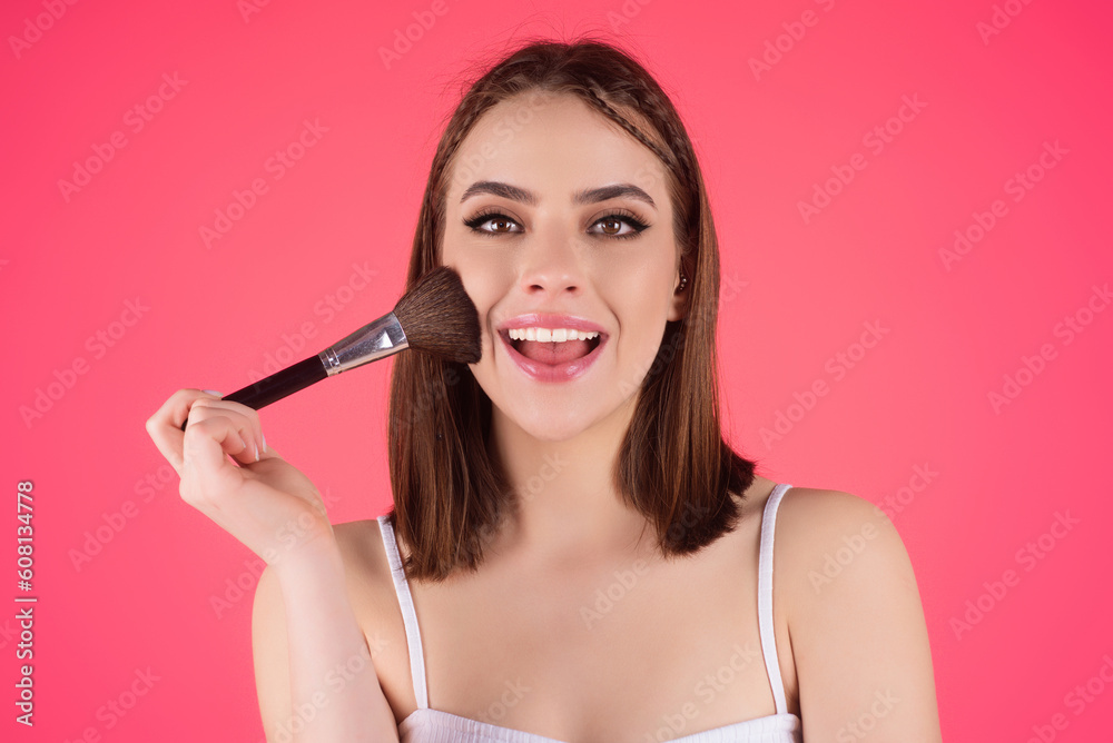 Studio portrait of a woman applying cosmetic tonal foundation on face using makeup brush. Beautiful girl doing contouring apply blush on cheeks isolated on studio background. Studio portrait of a woman applying cosmetic tonal foundation on face using makeup brush. Beautiful girl doing contouring apply blush on cheeks isolated on studio background.