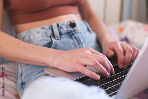 A girl works from home  female hands on a laptop keyboard close-up