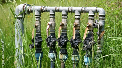 Closeup of water supply pipe pump valve and levers surrounded by tall grass photo