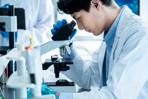 A male scientist conducting research under a microscope