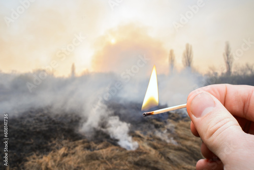 Burnt field in countryside with burning match on the foreground. Concept of big wildfire caused by a match